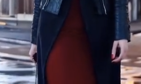A screenshot of a video of a woman walking, where her thumb is approximately as long as all her other fingers